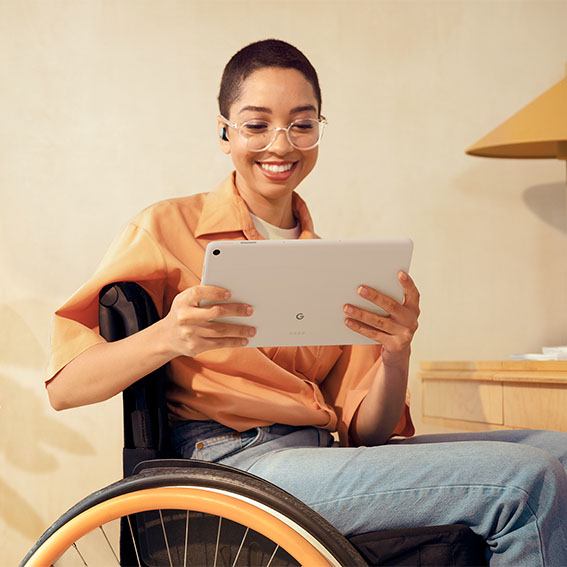 Kvinna i rullstol som använder Google Pixel Tablet i sitt hem