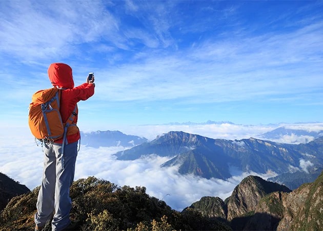 En kvinna tar ett foto med sin smartphone på vackert landskap.