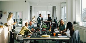 A group of employees in open office landscape, having discussions in smaller group