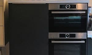 Två ugnar och kylskåp som är integrerade i köket för att passa in i övrig design och stil. 