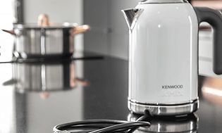 Köksö med en kastrull på en integrerad spishäll och en vit vattenkokare i snygg design som passar in i stilen.