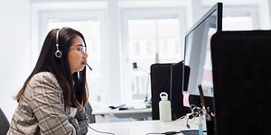 En kvinna talar i headset på kontor.