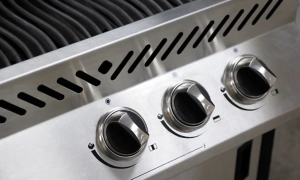 Svarta vred på en gasgrill i silver. 