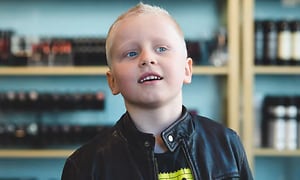 En ljushårig pojke som har fått en ny kortklippt frisyr och verkar nöjd med resultatet. 