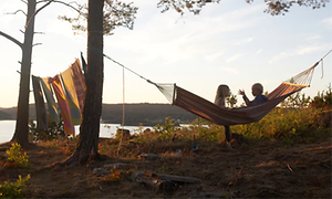 Två barn sitter i en hängmatta i naturen.