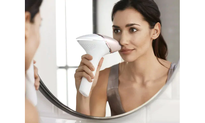 En kvinna använder Philips Lumea Prestige i ansiktet.