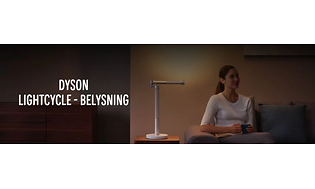 Dyson Lightcycle banner med kvinna som sitter i en soffa med sidobord och en bordslampa bredvid.