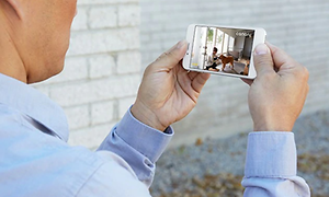 En man ser på övervakningsvideo via sin smartphone.