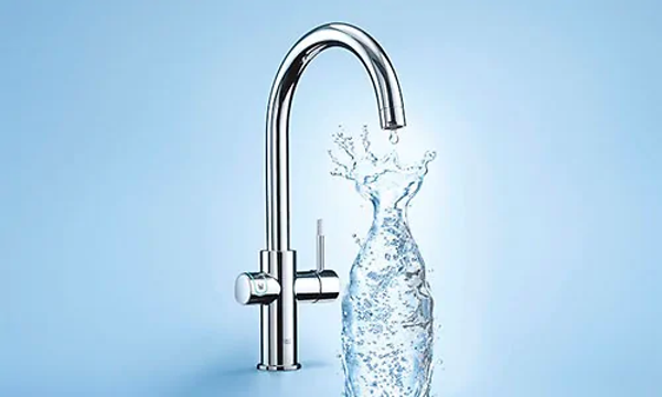 Grohe Blue vattenkran som fyller vatten i en genomskinlig karaff som bildas av vattnet. 