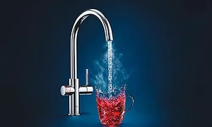 Grohe Red vattenkran med vatten som rinner ner i ett rött "fiktivt" glas.  