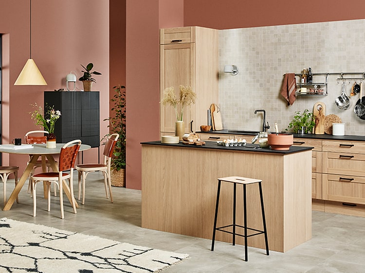 Stort öppet kök i ljus träfärg från Epoq Shaker Natural Oak. Mörkrosa väggar och runt köksbord med stolar. 