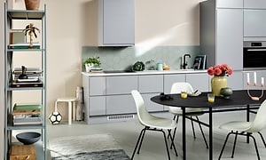 Ljusgrått kök från Epoq Integra Steel med svart köksbord med vita stolar. 