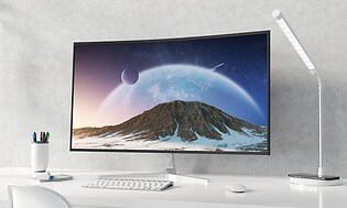 Stor datorskärm på ett vitt skrivbord med fjällvy på skärmen och planeter.