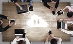 Multiple people around a table using cloud storage to work together