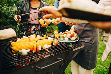 Människor som står runt en kolgrill som grillar grönsaker