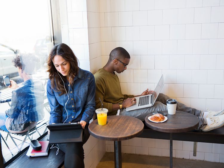 Två personer som sitter på ett kafé med bärbara datorer