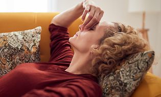 Kvinna med huvudvärk som ligger på en soffa