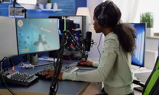 Gaming - Tjej sitter framför en gaming dator och streamar.