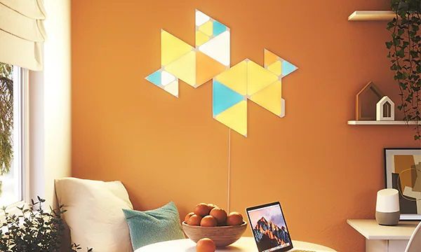 Gul, blå, och orange-färgad Nanoleaf på väggen i ett rum med orange vägg. 