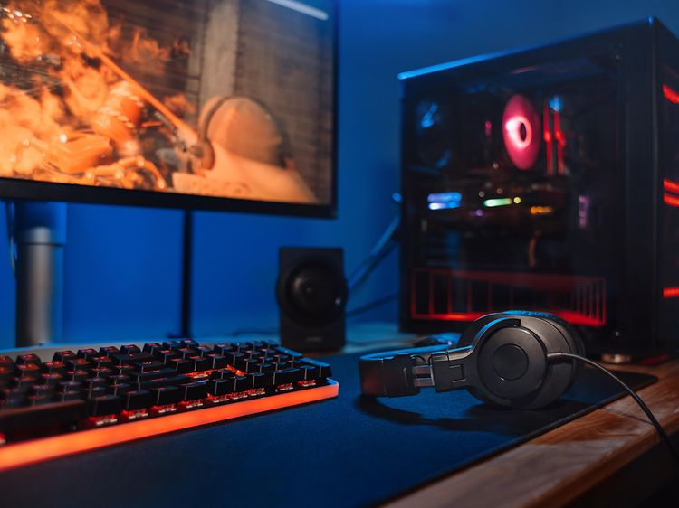 Gaming - PC-setup med skärm, skrivbord, tangentbord och hörlurar.