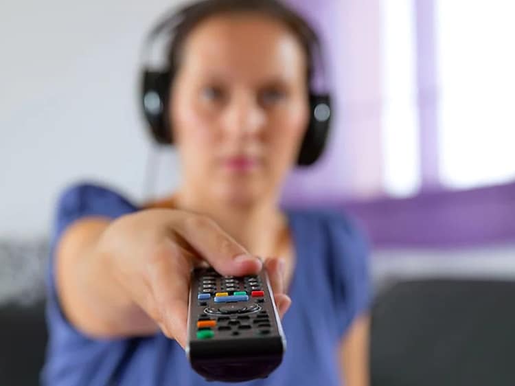 A woman wearing headset pointing with a TV remote control