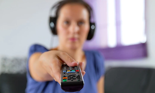 A woman wearing headset pointing with a TV remote control
