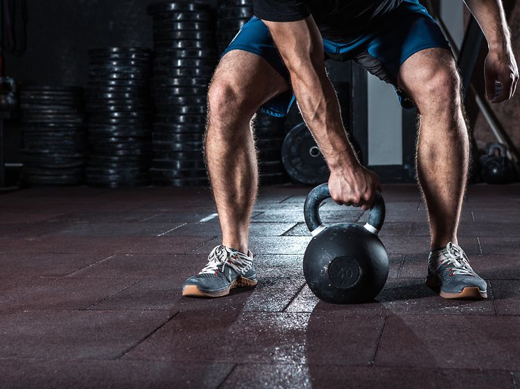 Man på väg att lyfta upp en kettlebell under ett träningspass.