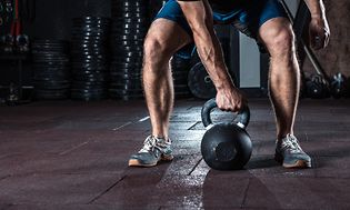 Man på väg att lyfta upp en kettlebell under ett träningspass.