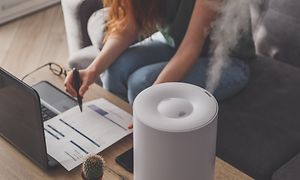Kvinna som arbetar på en bärbar dator med luftfuktare på bordet