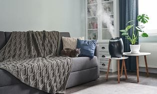 Svart luftfuktare på ett vitt bord bredvid en soffa i ett vardagsrum