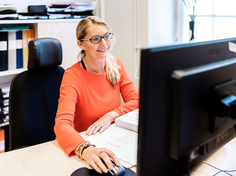 Kvinna som sitter framför en datorskärm på ett kontor