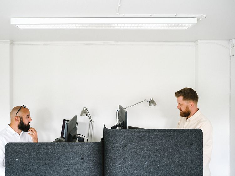 Två män på ett kontor som arbetar med sina datorer