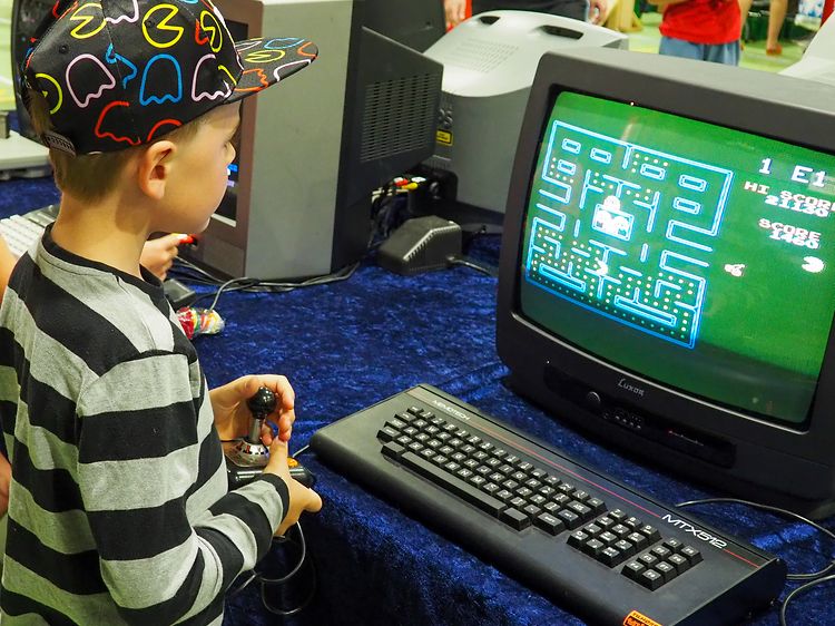 Liten pojke som spelar pacman på en gammal tjockteve