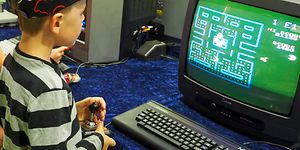 Liten pojke som spelar pacman på en gammal tjockteve