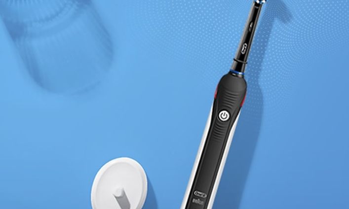 Oral-B Pro 2 elektrisk tandborste med laddare med blå bakgrund.