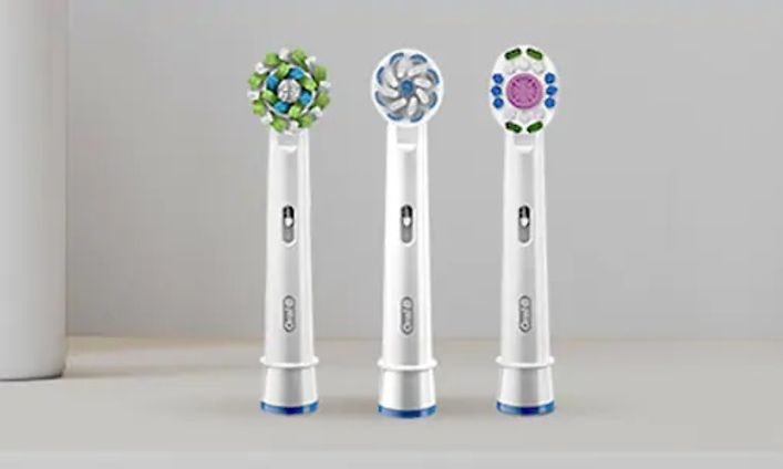 Tre olika tandborsthuvuden från elektriska tandborstar från Oral-B, med olika färger på stråna.
