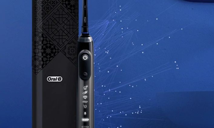 Oral-B Genius X svart elektrisk tandborste med resefodral på högkant med blå bakgrund.