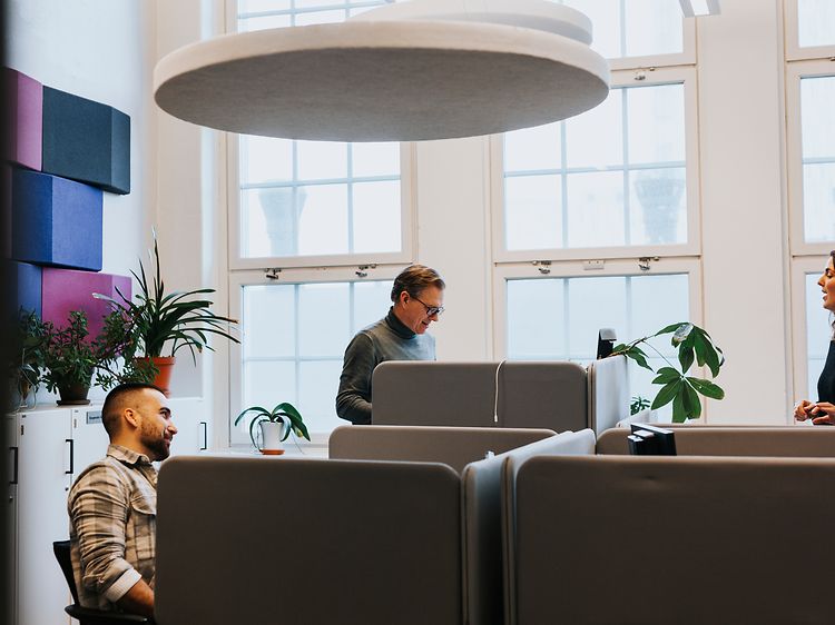 Två män och en kvinna vid deras skrivbord på ett kontor
