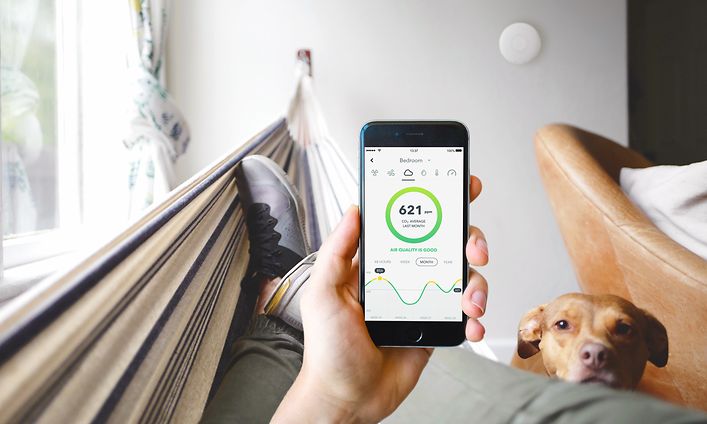 Person som håller i en smartphone med Airthings-appen på skärmen