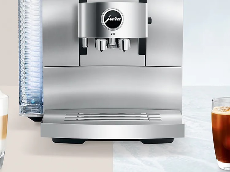 Silverfärgad kaffemaskin med två färdiga kaffedrycker på var sin sida, en med mjölk och en utan. 