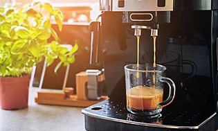 Kaffemaskin på ett bord och en kopp kaffe