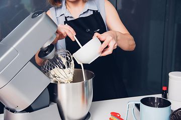 Kvinna som bakar en kaka med en köksmaskin