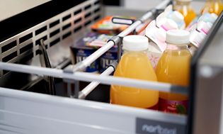 Utdragbar kylande låda från Norcool, med youghurtbägare, mjölkpaket och apelsinjuice på flaska.