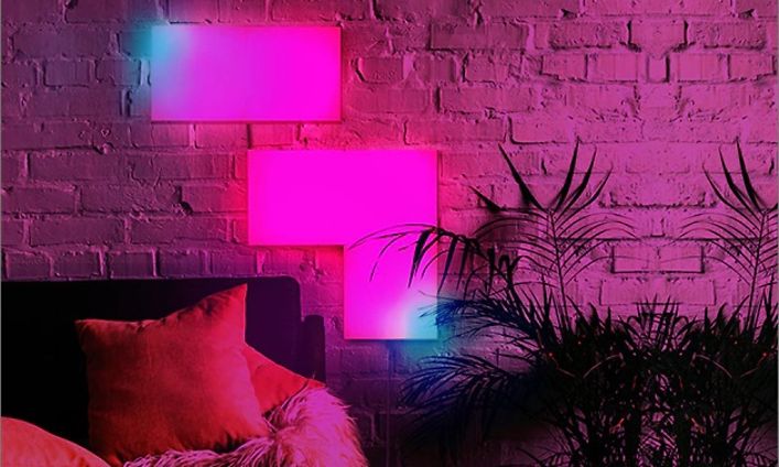 LIFX Tile med rosa och blått ljus på vägg i vardagsrum. Hörnet på en soffa och en stor krukväxt syns också. 