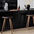 Köksö med svart bänkskiva i dekton material med barstolar och köksprylar på bänken. 
