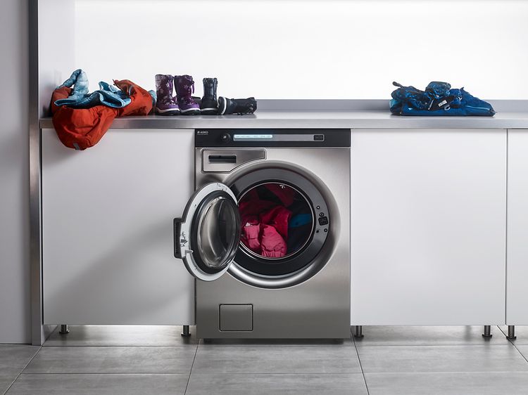 Asko Pro tvättmaskin och en bänk med barnkläder på