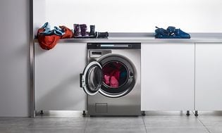 Asko Pro tvättmaskin och en bänk med barnkläder på