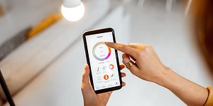 Kvinna som kontrollerar lampor med hennes telefon