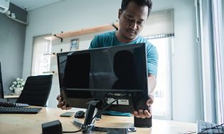 Tekniker installerar en datorskärm på ett kontor