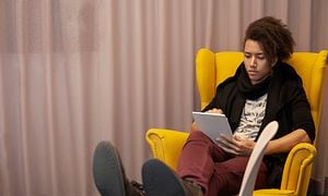 Kvinna sitter på en gul stol med en iPad